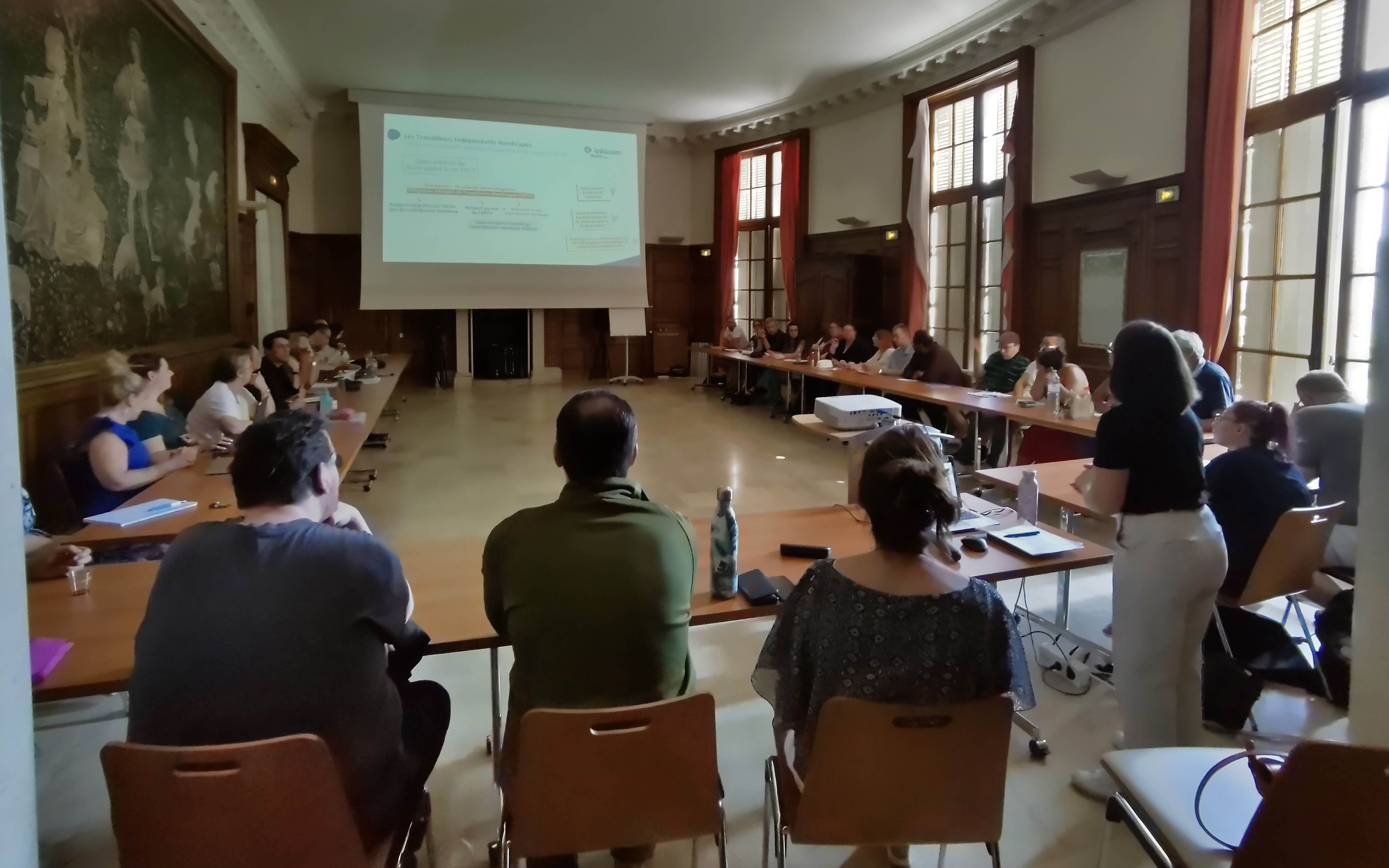 personnes autour d'une table avec écran et visio conférence