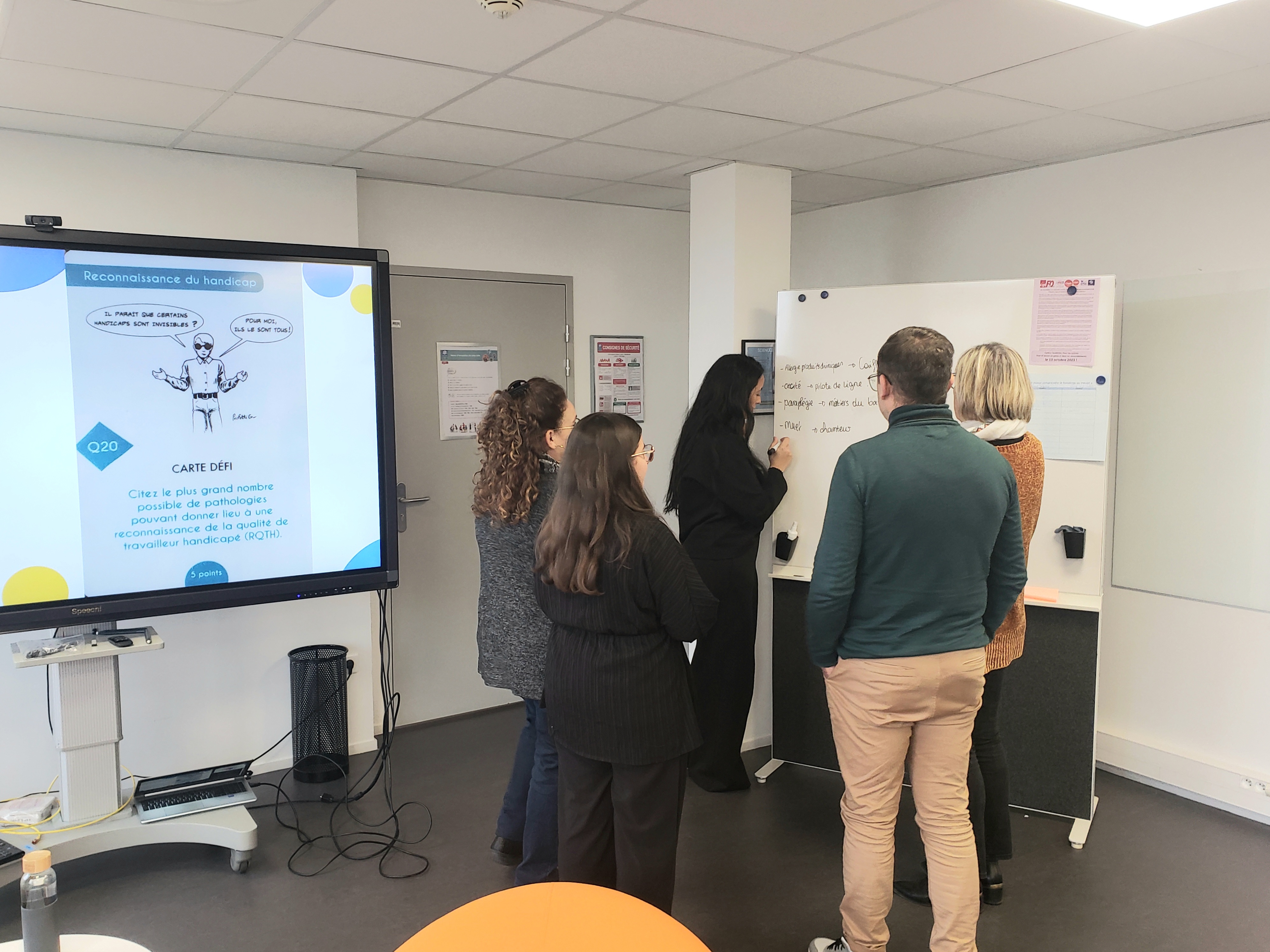 plusieurs personnes en train de travailler autour d'un tableau