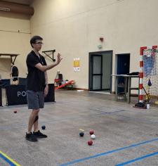 Personne debout dans un gymnase avec des boules de boccia parterre à côté de lui